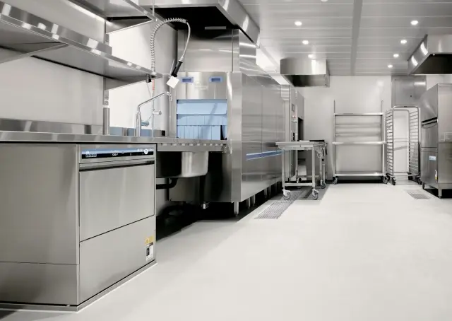 Cocina industrial de acero inoxidable con lavavajillas y estanterías metálicas